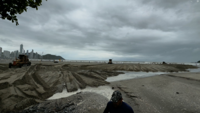 FOTOS: após temporal, praia de Balneário Camboriú tem banhistas em meio a sujeira e máquinas de limpeza